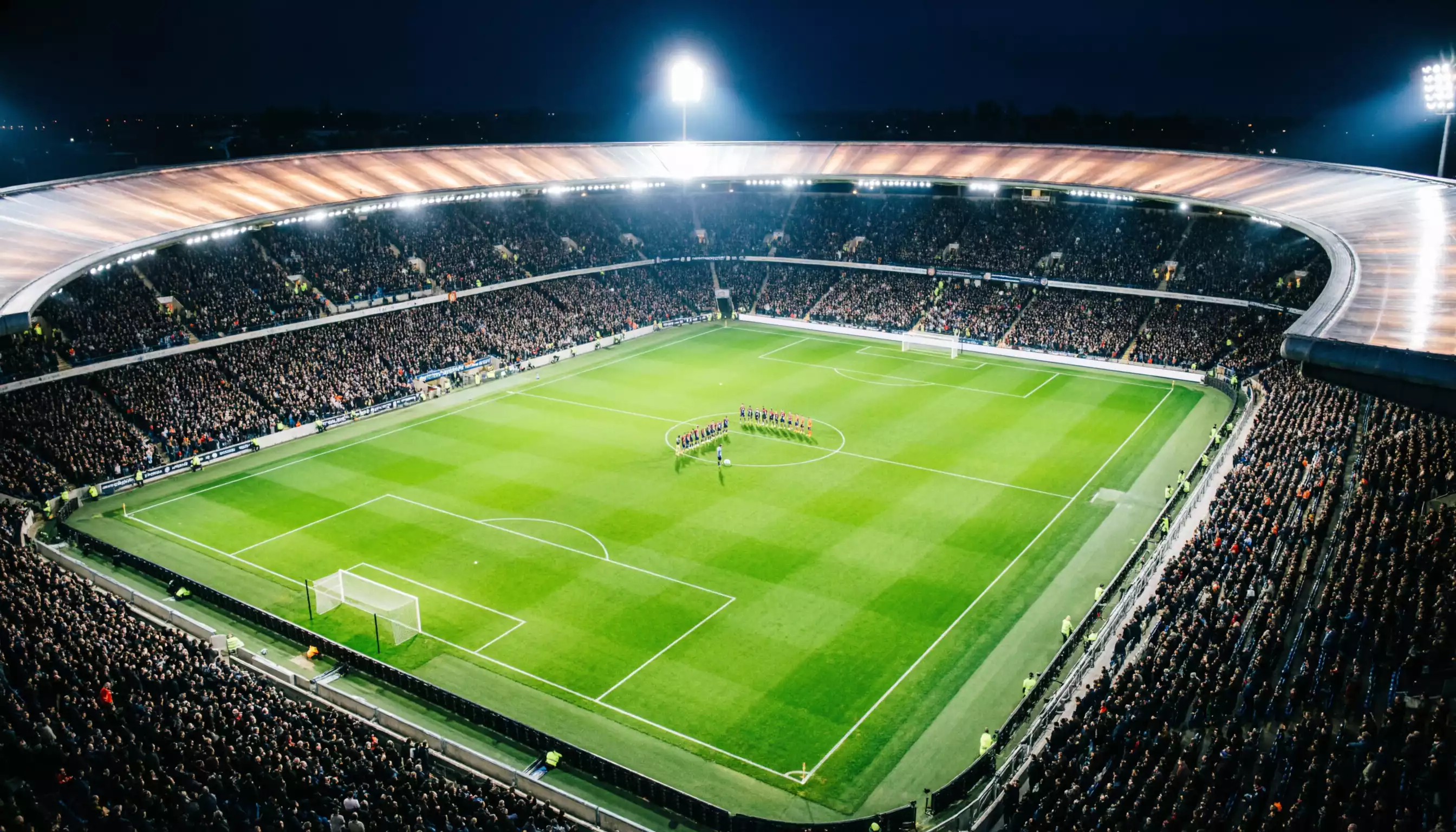Quattro bandiere europee che sventolano su aste davanti a un campo di calcio verde