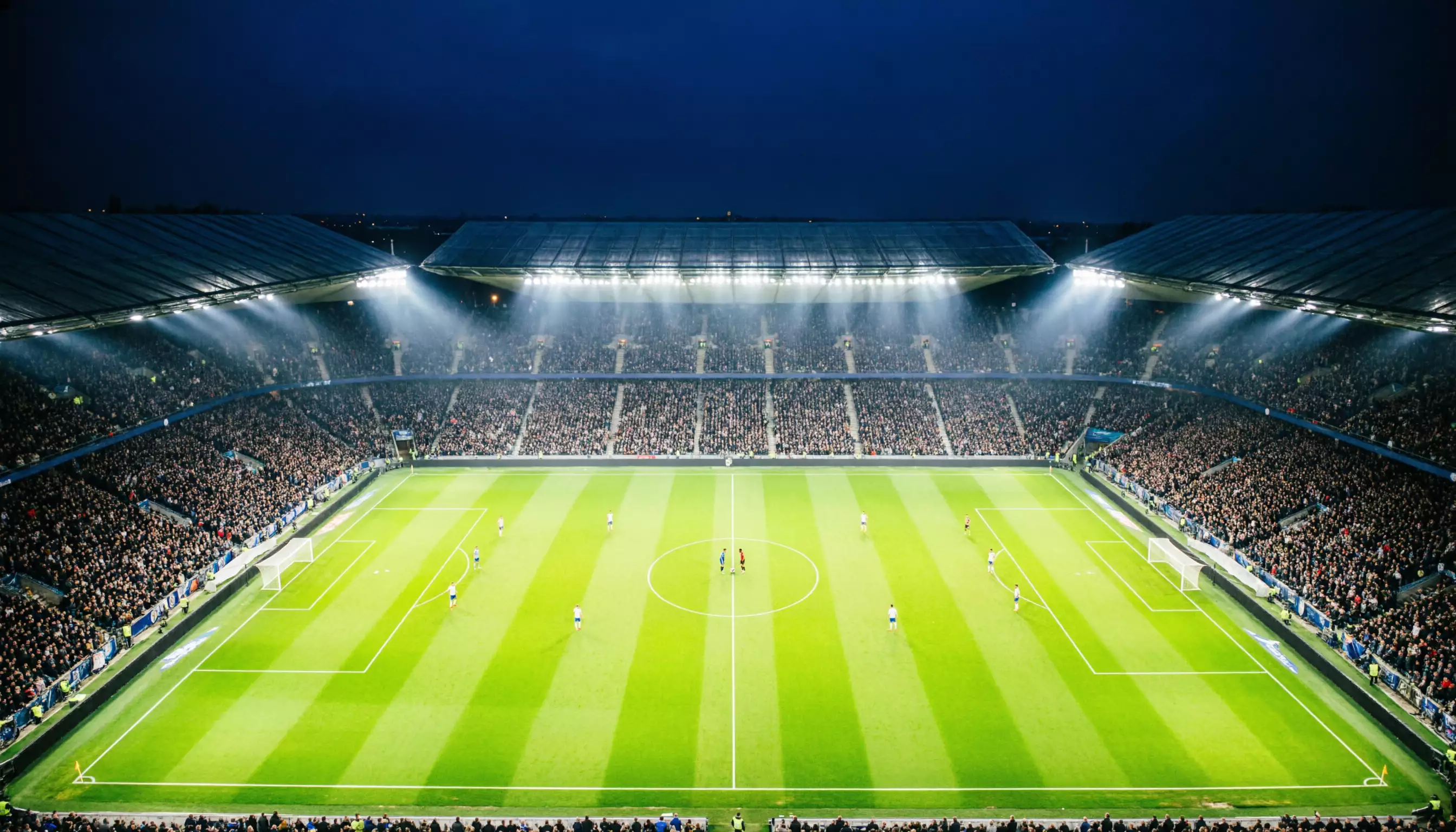 Stadio di calcio europeo illuminato di notte con il campo verde perfettamente visibile dall'alto
