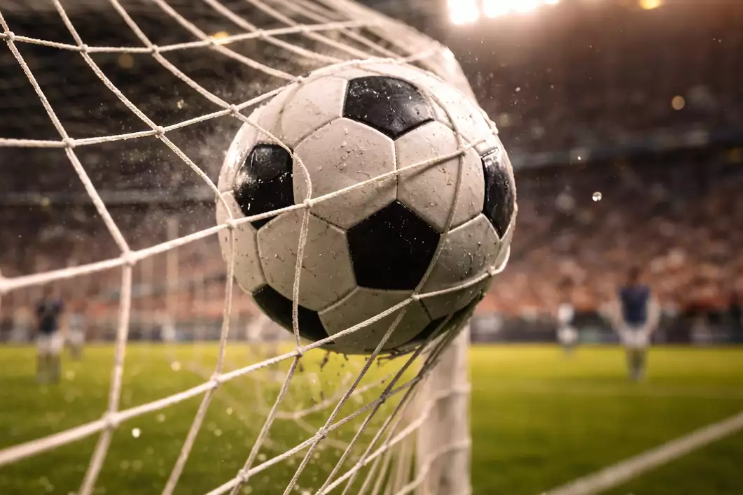 Pallone da calcio che entra in rete durante un'azione di gioco in uno stadio illuminato